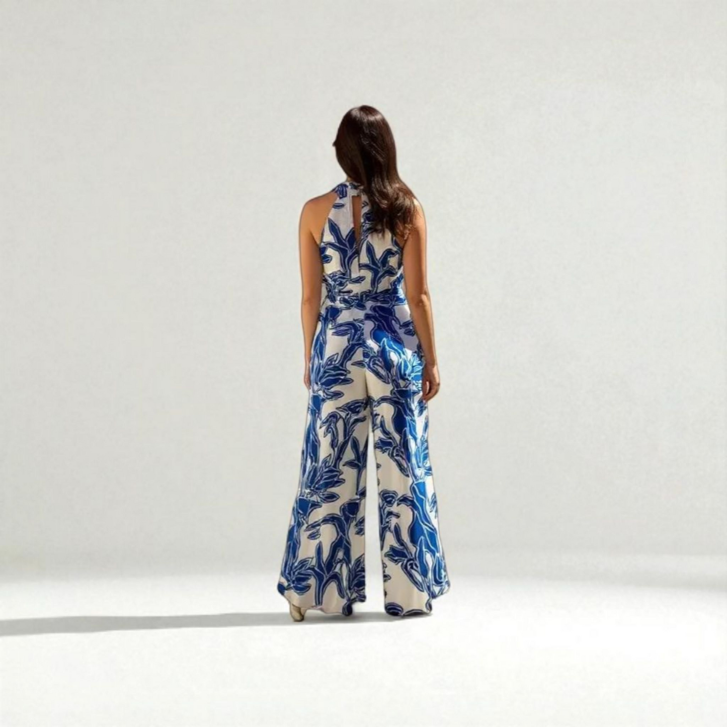 Woman wearing a blue and white floral jumpsuit on a white background